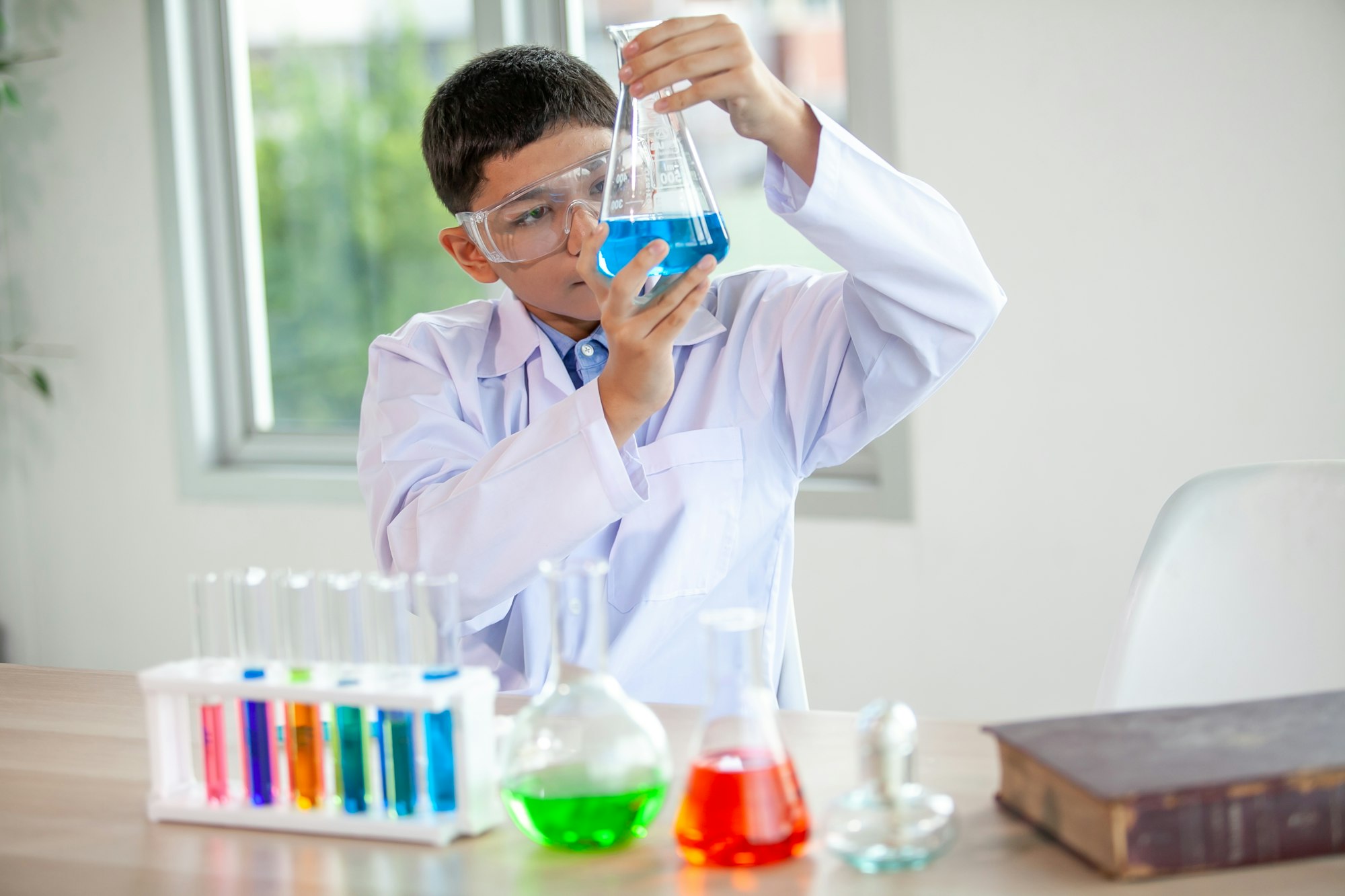 Little boy mixes chemicals in beakers. kids with test tube making experiment at school laboratory.