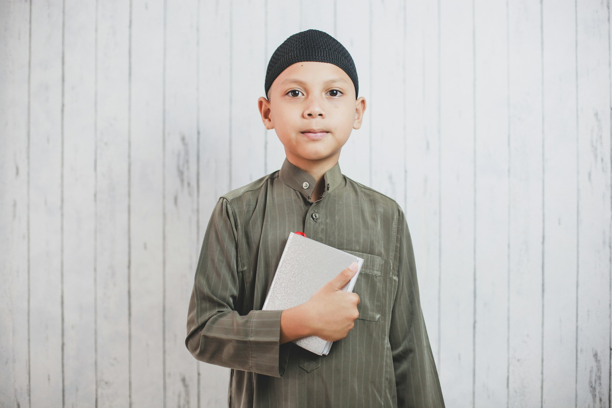 Muslim boy holding Holy Quran and smiling